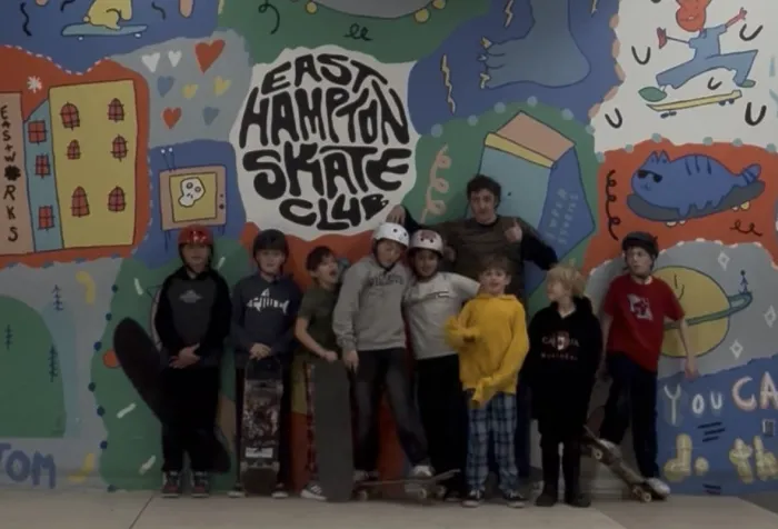 Kids wearing helmets pose with skateboards