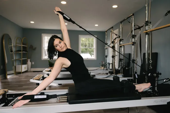 A woman stretches on a Pilates machine