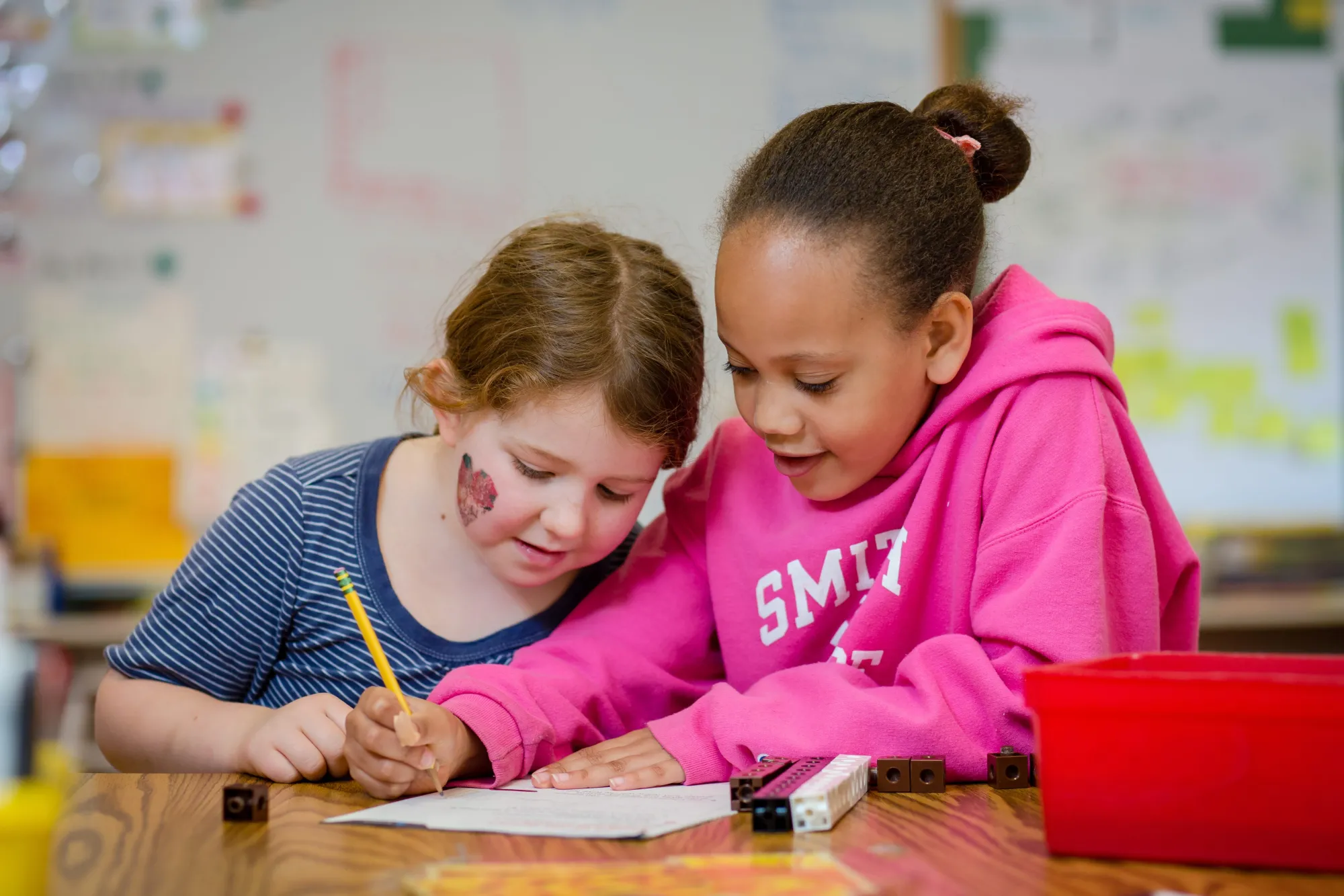 Two young girls work on math homework together.
